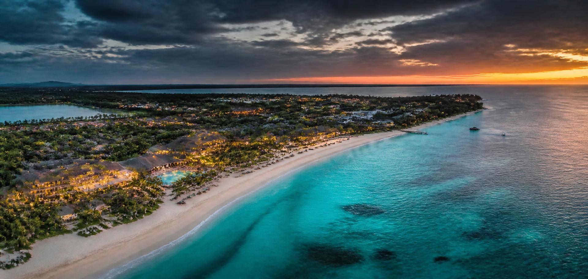 Aerial view of a luxury beachfront resort on a turquoise coastline at dusk